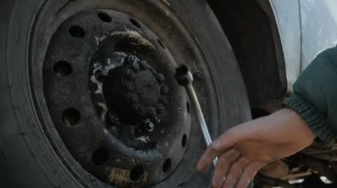 Bir tamirci ingiliz anahtarı kullanarak araba tekerleğini tamir ediyor..