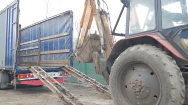 Traktör kazıcısı uzun bir kamyon platformuna düştü