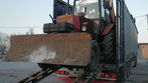 Traktor grävmaskin störtar på en lång lastbil plattform — Stockvideo