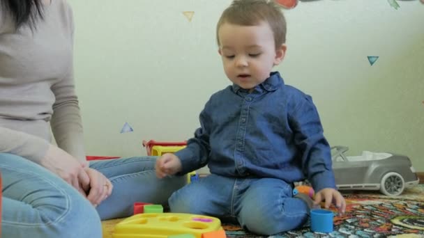 Un enfant joue avec maman jouets assis sur le sol — Video