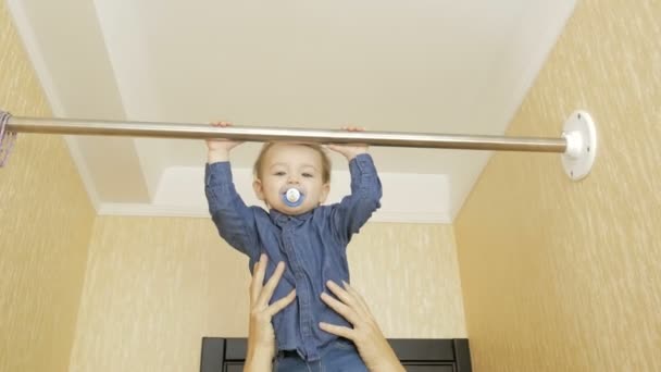 Niño tirando hacia arriba en la barra horizontal instalada en casa . — Vídeos de Stock