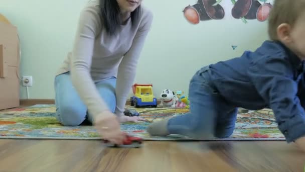 Un niño juega con juguetes de mamá sentados en el suelo — Vídeo de stock