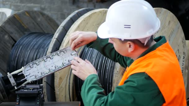 Un ingeniero de comunicaciones trabaja con un cable de fibra óptica. — Vídeos de Stock