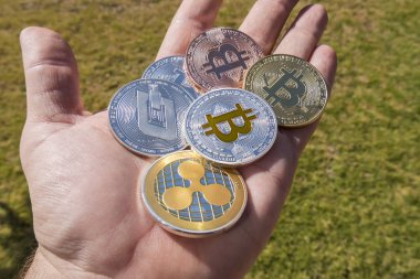 Cryptocurrency coins in a hand; Bitcoin, Ripple, Dash clipart
