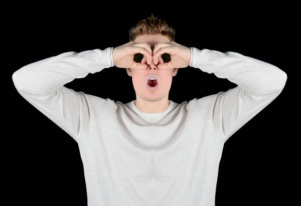 Europäischer junger überraschter Mann mit Sonnenbrille, der im Fernglas isoliert auf schwarzem Hintergrund schaut — Stockfoto