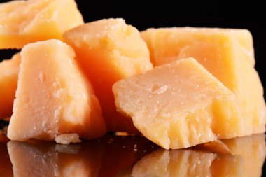 Yansıma bir siyah parlak masada parmesan peyniri. Siyah arka plan üzerine izole Parmesan peyniri.