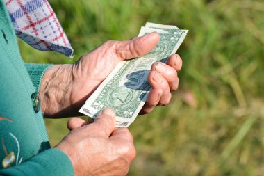 Yaşlı kadın para onun elinde tutuyor. Yaşlı bir kadın ile dolar onun elinde. Yoksulluk sadaka