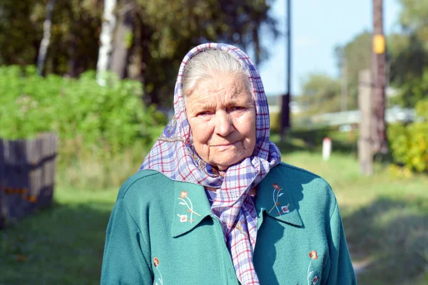 Bir eşarp yaşlı bir kadın. Yalnız yaşlı bir köyde duran kadın portresi
