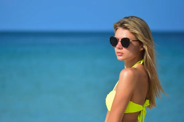 Sprawny, piękną, młodą kobietę w sexy bikini żółty nad morzem plaża i niebieski — Zdjęcie stockowe