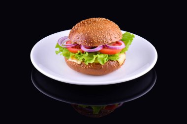 Siyah arka plan üzerine izole taze lezzetli burger. Lezzetli ve iştah açıcı çizburger beyaz tabakta. Vejetaryen burger