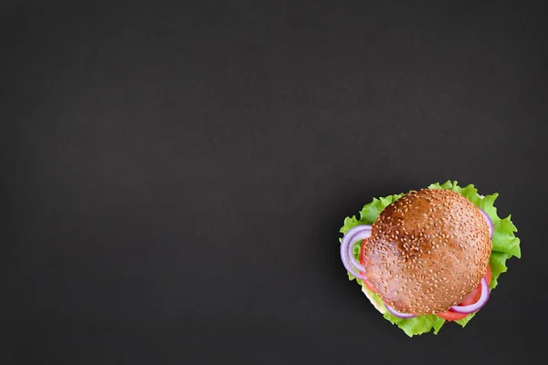Fresh tasty burger Top view on black background. Tasty and appetizing cheeseburger. Vegetarian burger with place for text — Stock Photo, Image