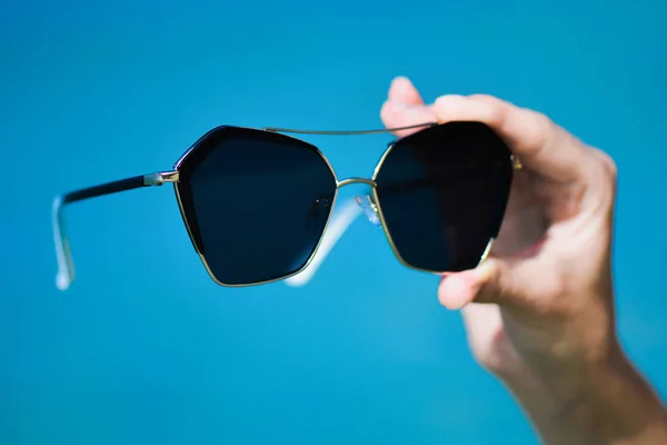 Mujer mano celebración gafas de sol en tropical playa mar — Foto de Stock