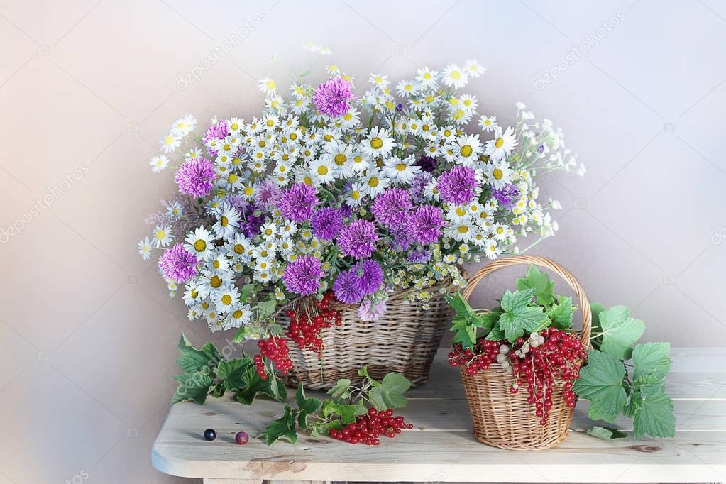 Wild flowers in a vase and berries in the basket.