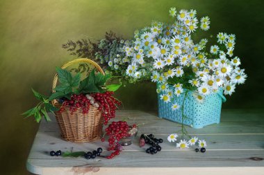 Kır çiçekleri ve olgun, kırmızı çilek bir sepet içinde. 