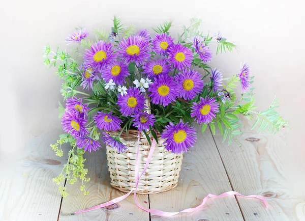 Still life with a bouquet of asters in a basket on white — Stock Photo, Image