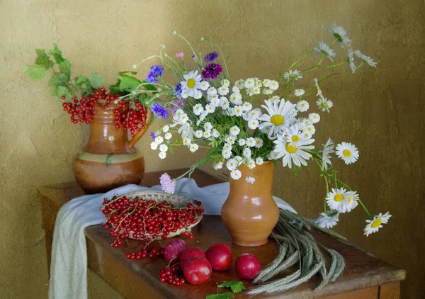 Berry pruimen, krenten en bloemen op tafel — Stockfoto