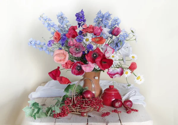 Berry pruimen, krenten en bloemen op tafel — Stockfoto