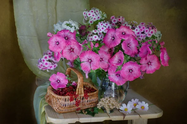 Een boeket van mooie bloemen en bessen in een mandje. — Stockfoto