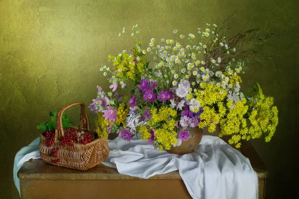 Egy csokor gyönyörű virágok és bogyók egy kosárban. — Stock Fotó