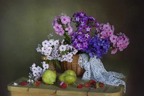 Still life with a bouquet of pink and purple Phlox pears, raspberries isolated on a green background