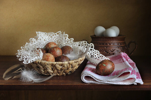 Chicken egg in a clay vase on a napkin, feathers . Easter still life in the old style