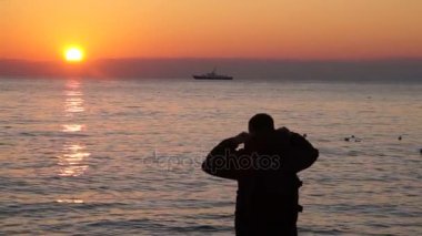 Adam sahilde gün batımını izlemek