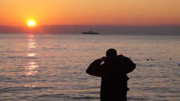 O homem na praia a ver o pôr do sol — Vídeo de Stock