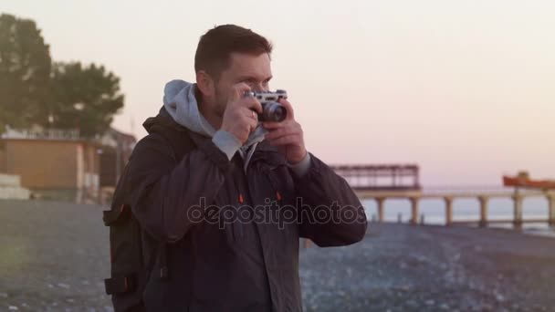 Человек на пляже фотографирует закат — стоковое видео