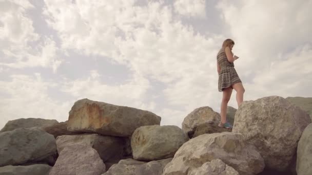 La chica camina en la cima de la montaña y mira a la distancia — Vídeo de stock