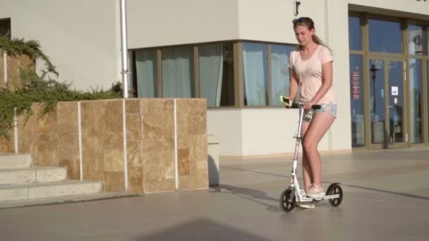 Menina em uma scooter com um smartphone, câmera lenta — Vídeo de Stock