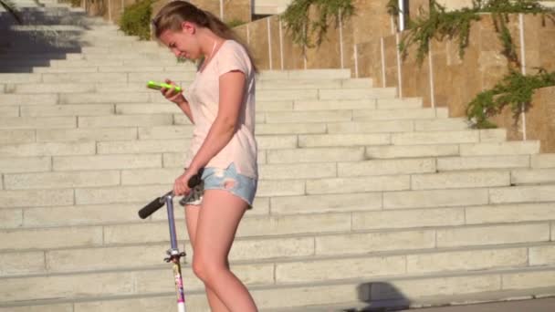 Fille sur un scooter avec un smartphone, au ralenti — Video