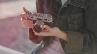 Tatilde olan bir kız film kamerasıyla deniz batımının fotoğraflarını çekiyor.