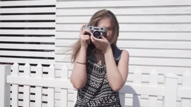 Ragazza con una fotocamera vintage su uno sfondo bianco, cabina da spiaggia in legno — Video Stock