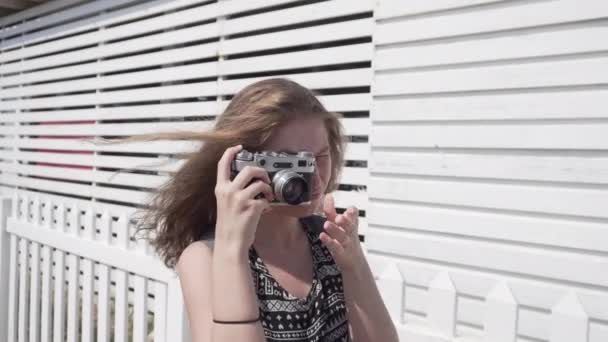 Дівчина з старовинною камерою на білому, дерев'яному пляжному фоні кабіни — стокове відео