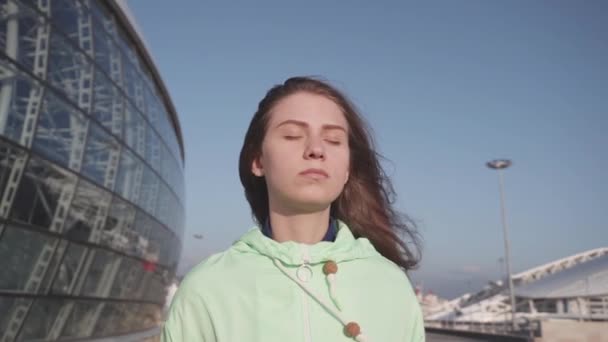 Eşofmanlı özgür kız şehirde meditasyon yapıyor. Güneşin ve rüzgarın tadını çıkarıyor. — Stok video