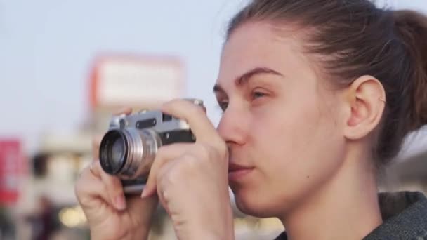 Дівчина з вінтажною кінокамерою робить швидкий знімок вечірнього міста — стокове відео