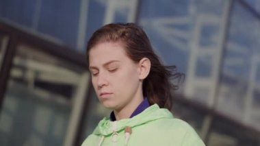 Yakın plan, bir kız şehir caddesinde yürüyor, rüzgar saçlarını büyütüyor.