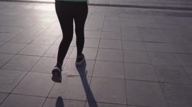 Spor malzemeleri içinde bir kız şehir caddesinde koşuyor.