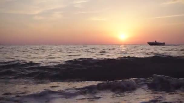 Лодка плавает по морю на фоне заката — стоковое видео