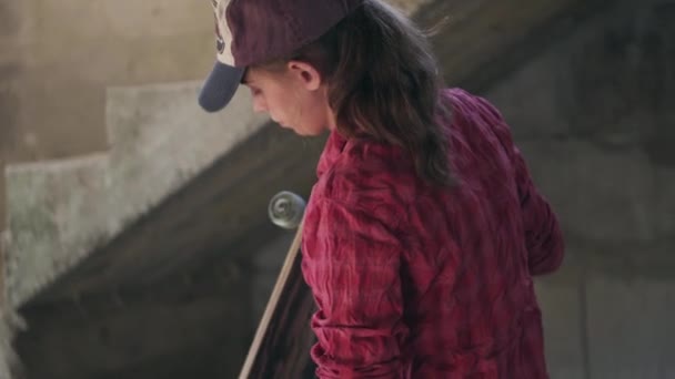 Молодая девушка со скейтбордом в мастерской — стоковое видео