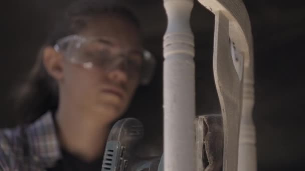 Κορίτσι ξυλουργός επισκευάζει έπιπλα αντίκες χρησιμοποιώντας μια μηχανή λείανσης — Αρχείο Βίντεο
