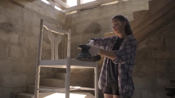 Girl carpenter repairs antique furniture using a sanding machine — Stock Video