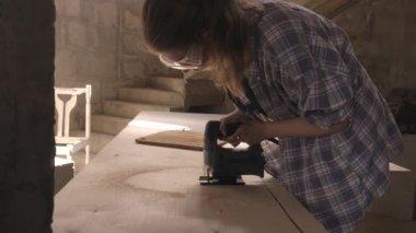 Dişi marangoz elektrikli bir yapbozla çalışıyor ve ahşap ürünleri işliyor.