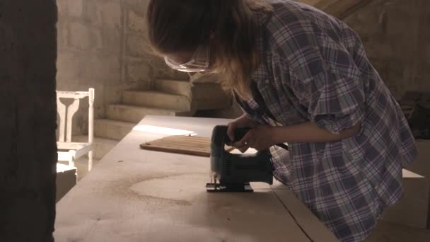 Женщина-плотник работает с электропилой и обрабатывает древесину — стоковое видео