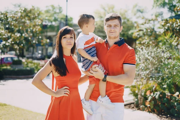 Красивая семья в красном, идущая по улице и парку — стоковое фото