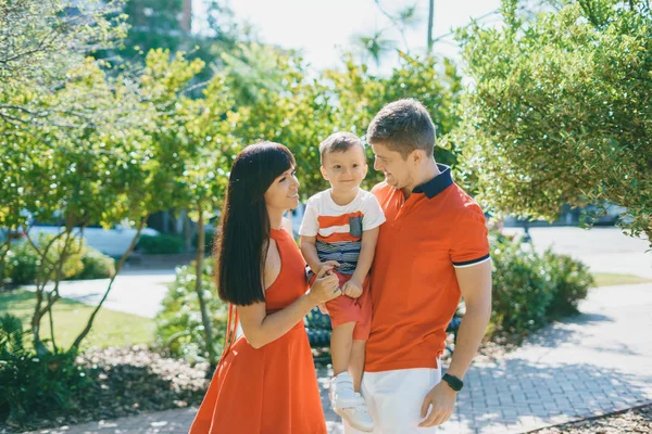 Hermosa familia en rojo caminando por la calle y el Parque — Foto de Stock