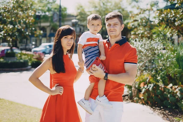 Hermosa familia en rojo caminando por la calle y el Parque — Foto de Stock