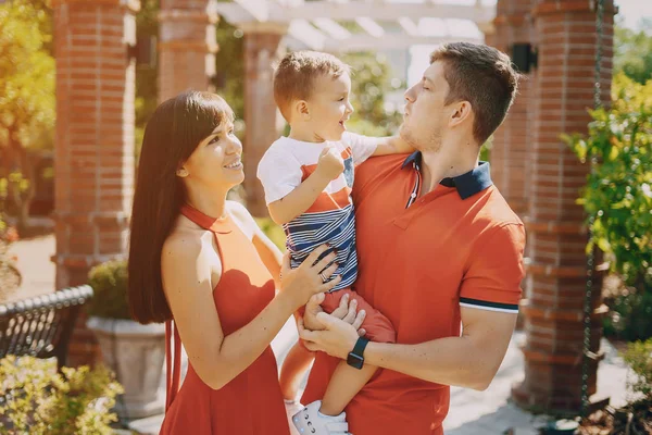 Красивая семья в красном, идущая по улице и парку — стоковое фото