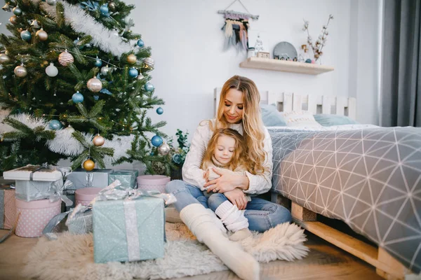 Mamá y su hija sentadas junto al árbol de navidad — Foto de Stock