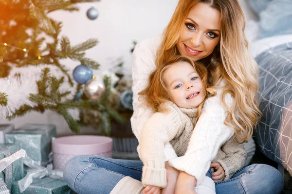 Madre e hija sentadas junto al árbol de navidad — Foto de Stock